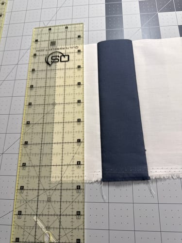 Customer's clear Quilters Select Non-Slip Ruler with thin grid lines on a cutting mat beside fabric.