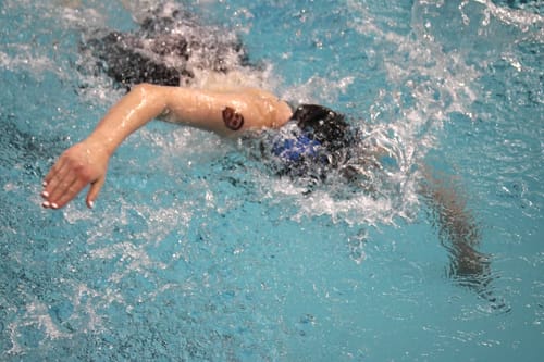 Reviewer swimming in a pool, showing the Custom Photo Face Temporary Tattoo staying on their wet arm.