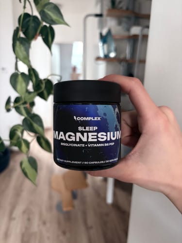 Customer holding a black jar of Complex Sleep Magnesium supplements in their hand.