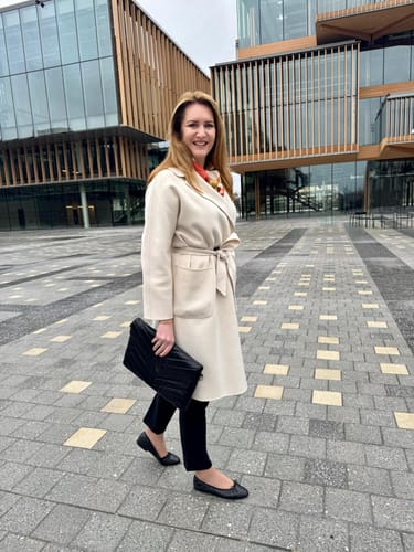 Customer walking outdoors while holding the black, chevron-quilted Essential Clutch.