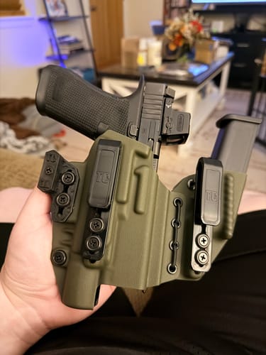 Customer holding their olive green AXIS ELITE holster with a firearm and spare magazine securely fitted inside.