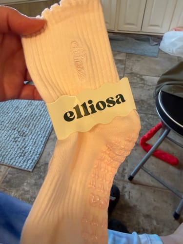 Reviewer holding a soft pink Dual-Direction Grip sock with its paper packaging sleeve.