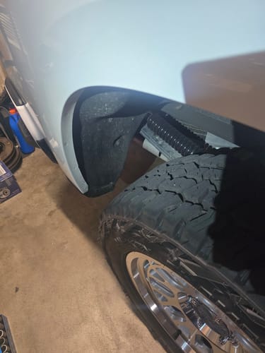 Customer's close-up view of the black HD Kit installed in the wheel well of a white Chevrolet Silverado.