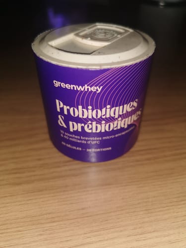 Un client présente le pot violet de Probiotiques & Prébiotiques, posé sur une table.