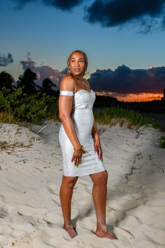 Reviewer standing on a beach at sunset wearing the shiny Silver Metallic Off Shoulder Bandage Dress.