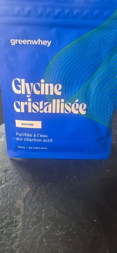 Un client montre le sachet bleu de Glycine cristallisée posé sur une surface sombre.