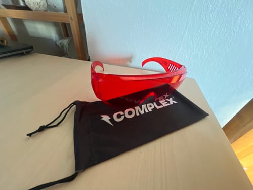 Reviewer's red VisionX glasses on a desk next to their black branded carrying pouch.