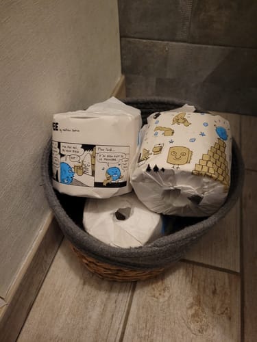 Plusieurs rouleaux de papier toilette du client dans un panier, mettant en avant l'emballage original en bande dessinée.