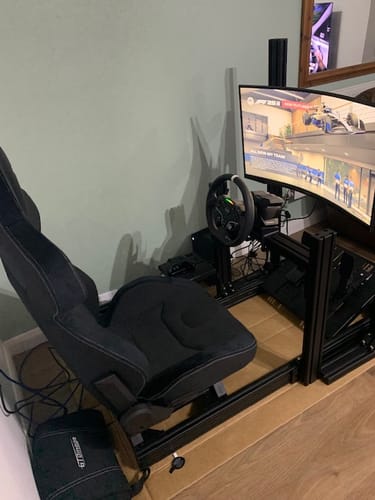 Reviewer's MOZA R3 Racing Wheel and Pedals installed in a black racing simulator rig with a seat and curved monitor.