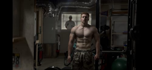 Reviewer standing shirtless in a home gym, wearing the camouflage-patterned Baggy Basketball Shorts.