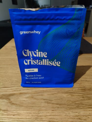 Le sachet bleu de Glycine cristallisée du client, posé sur une table en bois.