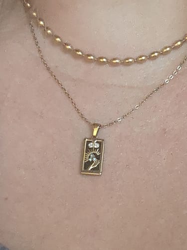 Close-up of a reviewer wearing the Golden Fortune Necklace with a tarot pendant, layered with another gold chain.