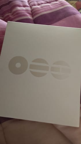 Customer's BTS - ARIRANG 5TH ALBUM in its simple white packaging box, resting on a striped comforter.
