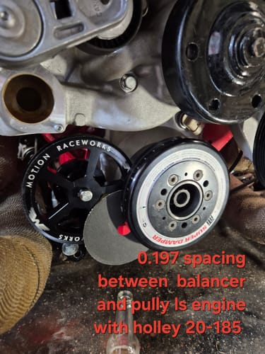 Customer's black Motion Raceworks 56 Tooth Pulley installed on an LS engine next to the balancer.