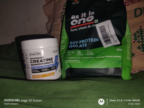 Customer's white tub of Wellcore Creatine Monohydrate placed on a green surface next to another supplement.