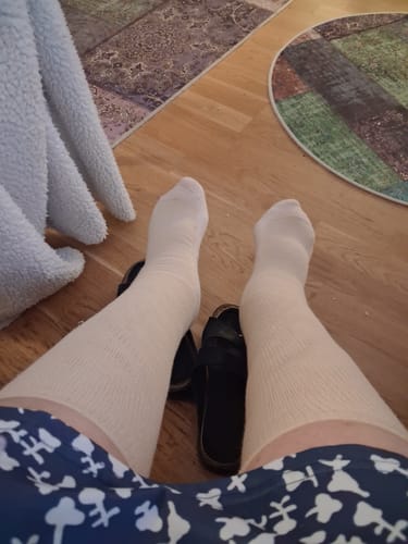 Recensent som visar ett par vita Diasocks Komfortstrumpor på sina fötter, sett ovanifrån.