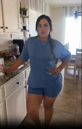 Clienta de pie en una cocina vistiendo el cómodo conjunto LumiSet™ azul.