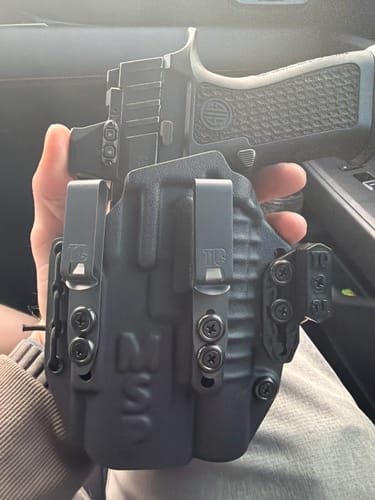 Reviewer holding a black holster with two 1.5" Discreet Carry Concepts clips attached.