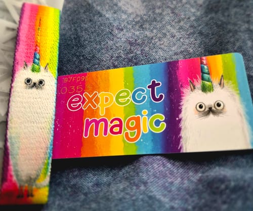 Customer's colorful Expect Magic Bracelet and matching card, showing a fluffy caticorn design against a rainbow background.