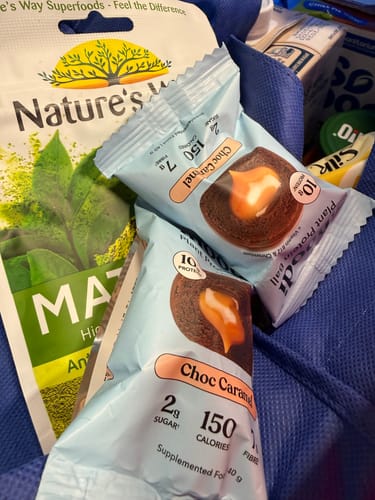 Customer's two Choc Caramel Plant Protein Balls in a blue shopping bag with other groceries.