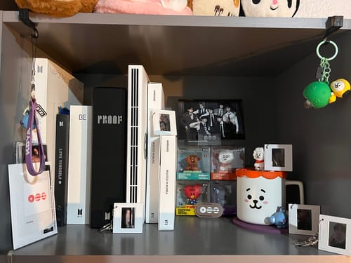 Reviewer's neat display of BTS albums and other merchandise on a dark shelf.
