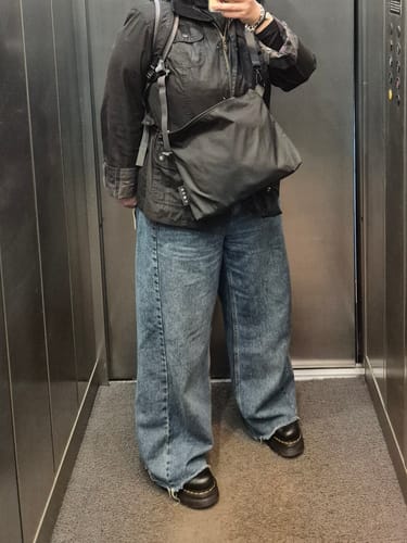 Customer wearing the black FIN Move bag crossbody over a jacket, showing its size in a daily outfit.