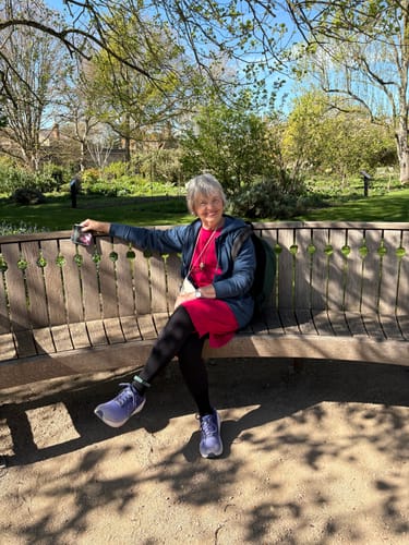 Customer wearing the blue Ryann Hoodie while sitting on a sunny park bench.