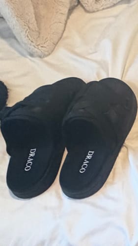 Customer's pair of black Blackout Dracos V2 slides resting on a white bedspread, with the DRACO logo visible.
