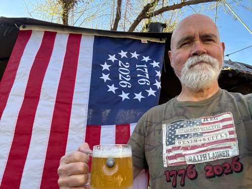 Reviewer holding a mug stands before the Betsy Ross flag from the Patriotic Decor Kit hung outdoors.