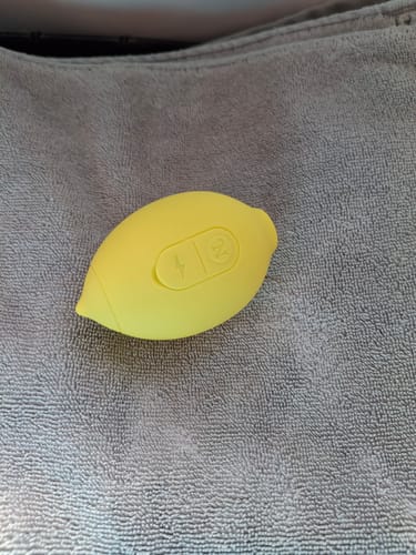Customer's yellow Lem Clitoral Massager resting on a grey towel.
