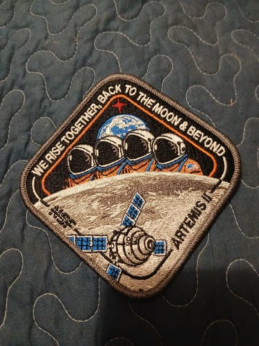 Customer's embroidered Artemis II Collectors Patch showing the mission design on a blue quilted surface.