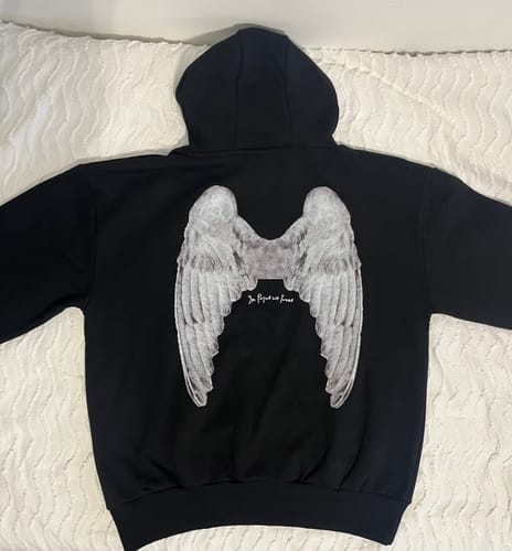 Customer's angel black hoodie laid flat, showing the back graphic print of large angel wings.