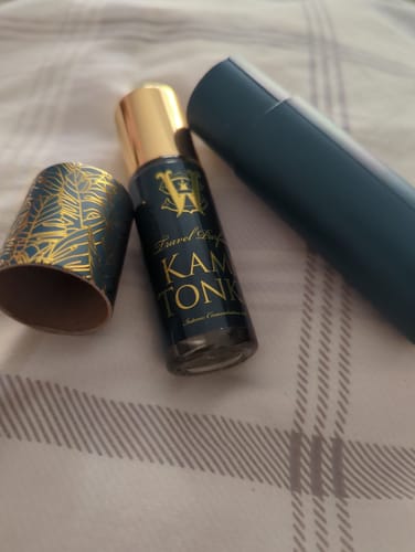 Reviewer's Kami Tonka perfume bottle next to its dark teal case with a gold-accented cap.