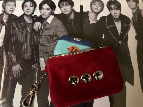 Customer's red BTS ARIRANG card holder showing the front with three silver insignias and a case peeking out.