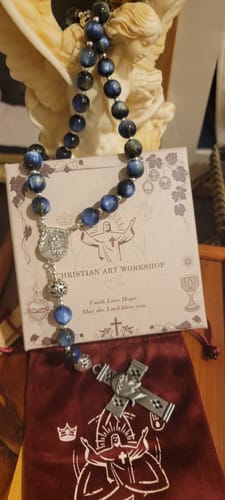 Customer's ornate blue beaded rosary displayed with its pouch and packaging card.