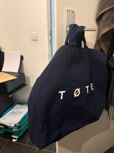 Reviewer's Navy Blue TØTE Bag hanging from a door handle.