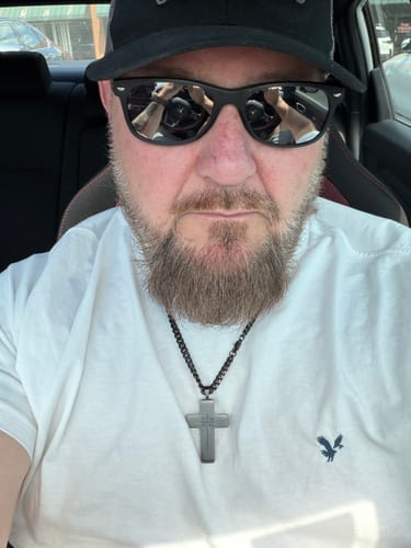 A reviewer showing the fit of the dark Never Forgotten Legacy Urn Cross Necklace against a white shirt.