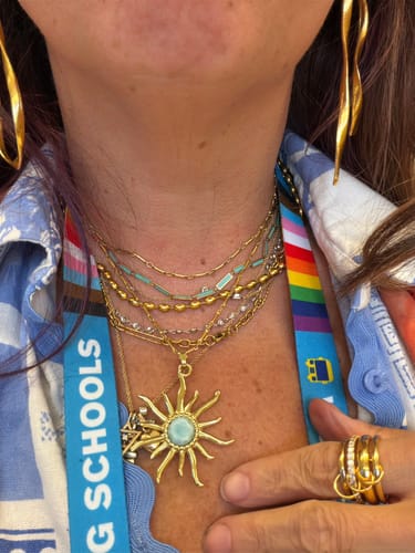 Reviewer wearing the Malaga Bead Necklace layered with other gold necklaces and a sun pendant.