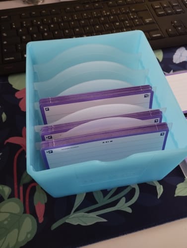 Client montrant la Flashbox bleu pastel pleine de fiches de révision organisées avec des séparateurs sur un bureau.