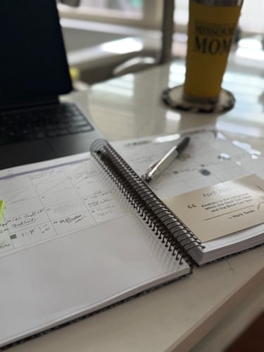 Customer's spiral-bound Scout Planner open on a desk, with handwritten entries in the calendar section.