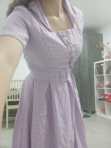 Reviewer wearing the purple plaid swing dress, showing the square neckline, button details, and matching belt.