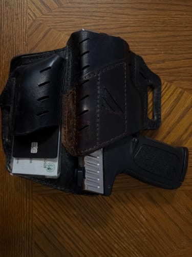 Customer's SPOTMINDERS Tracking Card PRO placed in a black leather gun holster next to a handgun.