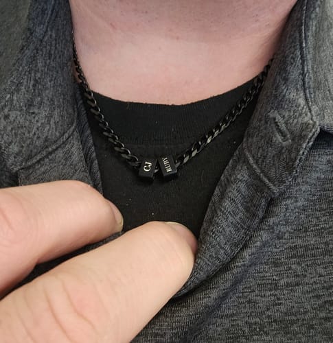 Customer wearing the black Legacy Necklace with two personalized beads engraved with 'CJ' and 'RUBY'.