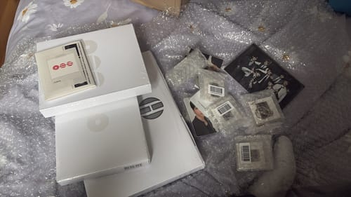 Reviewer shows their unboxed BTS ARIRANG 5TH ALBUM SET, with the albums and gift items spread out on bubble wrap on a bed.