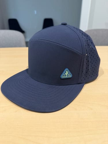 Customer's navy blue Big Flat Bill Structured Watersport Hat sitting on a table.