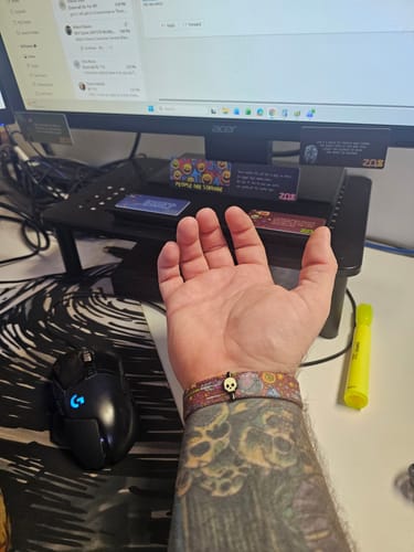 Customer wearing the Glow-In-The-Dark Skull Charm on a patterned bracelet on their tattooed arm.