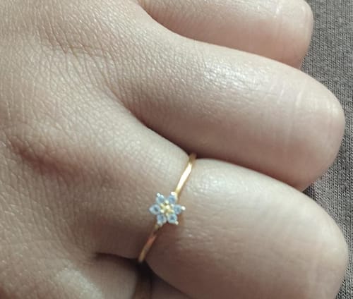 Close-up of a customer's finger wearing the delicate Golden Star Constellation Ring.
