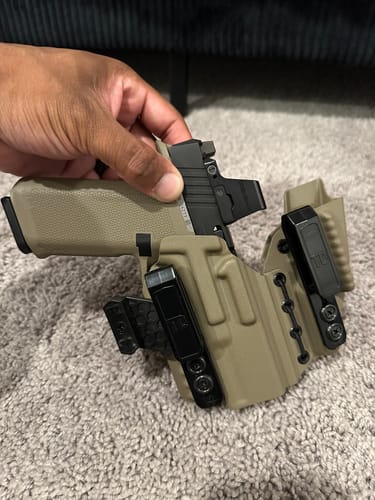Reviewer showing their tan AXIS ELITE holster with a pistol being placed inside.