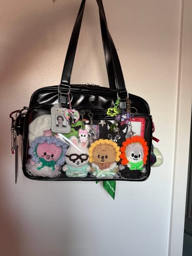 Customer's black COKO STAGE BAG decorated with plush toys and keychains in the clear front pocket.