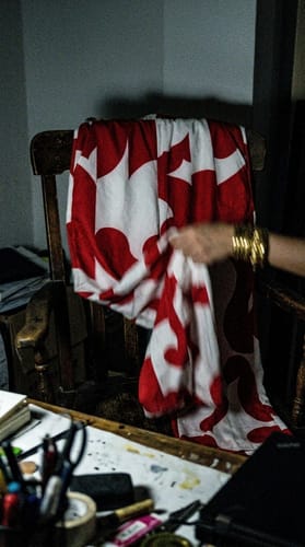 Reviewer holding their loose, red and white printed pants draped over a wooden chair.